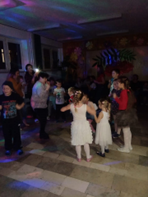 Uczniowie biorą udział w zabawach andrzejkowych, układają buty jeden za drugim, tańczą.