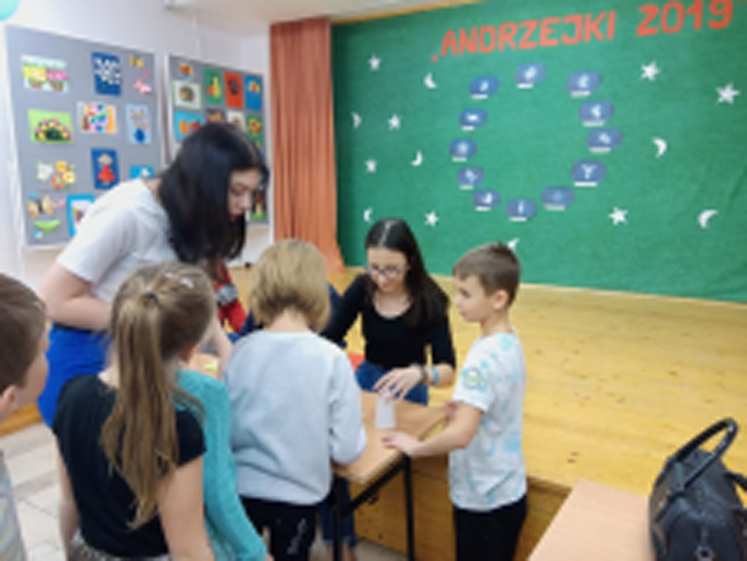 Uczniowie biorą udział w zabawach andrzejkowych, układają buty jeden za drugim, tańczą.