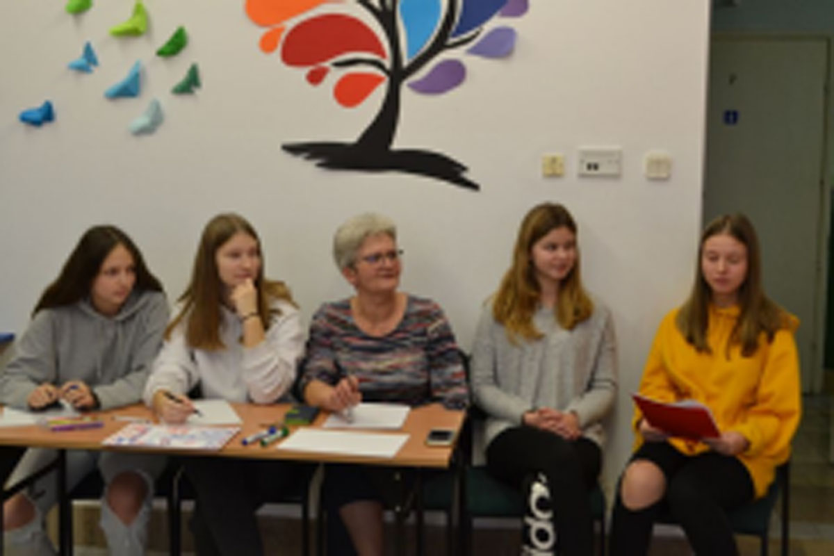 Uczniowie występują na scenie, trzymają mikrofony. Członkowie jury siedzą przy stoliku, wręczają dyplomy. Wspólne zdjęcie uczniów.