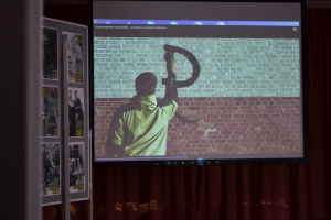 Zdjęcia przedstawiają salę, w której siedzą  uczniowie szkoły i oglądają prezentację.  Z frontu wystawione są stelaże, na których przypięte są zdjęcia przedstawiające Żołnierzy Wyklętych. Na jednym ze zdjęć przedstawiony jest dyrektor szkoły i nauczycielk