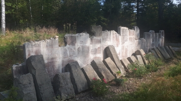 Uczniowie przy nagrobkach zapalają znicze.