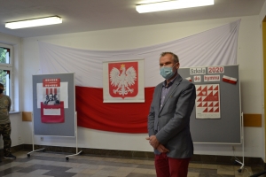 Na tle tablicy z biało-czerwonym sercem i napisem Serce dla Polski widoczna jest grupka dzieci w maseczkach. Jeden z chłopów ma uniesioną prawa rękę z palcami ułożonymi w znak zwycięstwa.SU Rabka