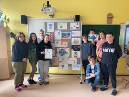 uczniowie stoją koło gazetki z pracami plastycznymi