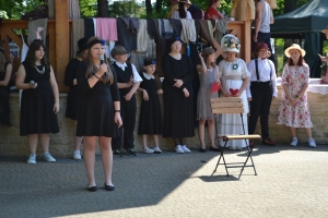 uczniowie przebrani w stroje z lat 20, 30,  tańczą, bawią się w stare gry, śpiewają, przedstawiają, oglądają teatrzyk
