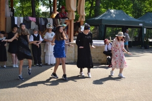 uczniowie przebrani w stroje z lat 20, 30,  tańczą, bawią się w stare gry, śpiewają, przedstawiają, oglądają teatrzyk