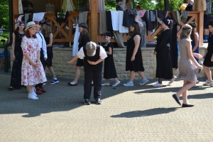 uczniowie przebrani w stroje z lat 20, 30,  tańczą, bawią się w stare gry, śpiewają, przedstawiają, oglądają teatrzyk