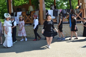 uczniowie przebrani w stroje z lat 20, 30,  tańczą, bawią się w stare gry, śpiewają, przedstawiają, oglądają teatrzyk