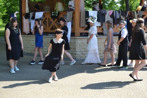 uczniowie przebrani w stroje z lat 20, 30,  tańczą, bawią się w stare gry, śpiewają, przedstawiają, oglądają teatrzyk