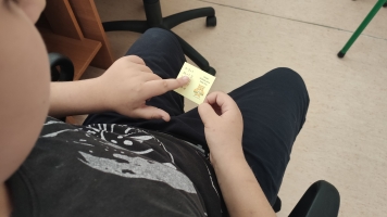 Uczniowie przy komputerach i stolikach. Układają wierze z plastikowych kubków, losują łyżeczki z zadaniami, grają w gry planszowe, rozwiązują zadania w programie komputerowym.