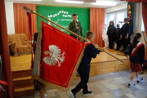 Uczniowie na scenie śpiewają pieśni. Koło sceny poczet sztandarowy, na scenie uczniowie przebrani w czarne stroje zaborców i  na biało za orła. Uczniowie składają znicze pod krzyżem.