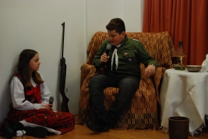 Uczniowie na scenie śpiewają pieśni. Koło sceny poczet sztandarowy, na scenie uczniowie przebrani w czarne stroje zaborców i  na biało za orła. Uczniowie składają znicze pod krzyżem.