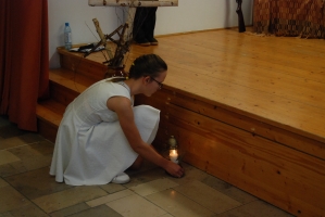 Uczniowie na scenie śpiewają pieśni. Koło sceny poczet sztandarowy, na scenie uczniowie przebrani w czarne stroje zaborców i  na biało za orła. Uczniowie składają znicze pod krzyżem.