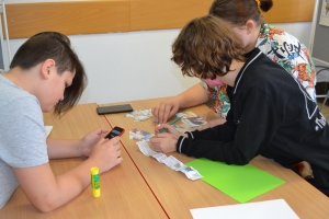 Uczniowie przy stolikach, rozwiązują krzyżówki, wykreślanki, rebusy.