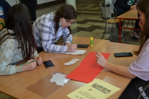 Uczniowie przy stolikach, rozwiązują krzyżówki, wykreślanki, rebusy.