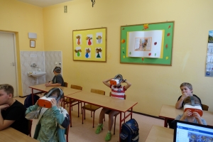 uczniowie przy stolikach w okularach vr