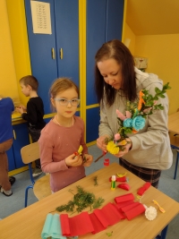 uczniowie przy stolikach wykonują palmy wielkanocne
