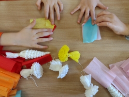 uczniowie przy stolikach wykonują palmy wielkanocne