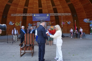 Występujący na scenie tańczą z pomponami, ze wstęgami. Na scenie dekoracja, pacynki Jacek i Agatka. Order Uśmiechu wręcza sekretarz Kapituły Orderu Uśmiechu i państwo Burcanowie.