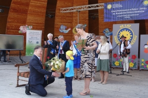 Występujący na scenie tańczą z pomponami, ze wstęgami. Na scenie dekoracja, pacynki Jacek i Agatka. Order Uśmiechu wręcza sekretarz Kapituły Orderu Uśmiechu i państwo Burcanowie.