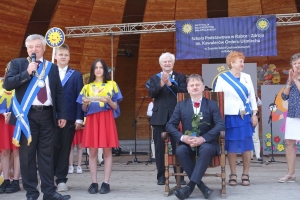 Występujący na scenie tańczą z pomponami, ze wstęgami. Na scenie dekoracja, pacynki Jacek i Agatka. Order Uśmiechu wręcza sekretarz Kapituły Orderu Uśmiechu i państwo Burcanowie.