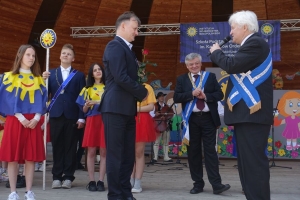 Występujący na scenie tańczą z pomponami, ze wstęgami. Na scenie dekoracja, pacynki Jacek i Agatka. Order Uśmiechu wręcza sekretarz Kapituły Orderu Uśmiechu i państwo Burcanowie.