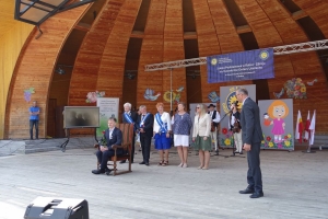 Występujący na scenie tańczą z pomponami, ze wstęgami. Na scenie dekoracja, pacynki Jacek i Agatka. Order Uśmiechu wręcza sekretarz Kapituły Orderu Uśmiechu i państwo Burcanowie.