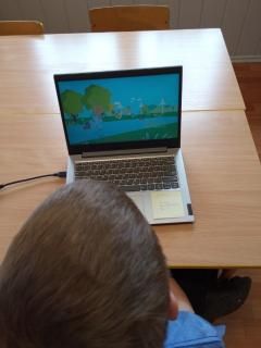 grafika przestawia komputer a w dolnej części fragment głowy ucznia